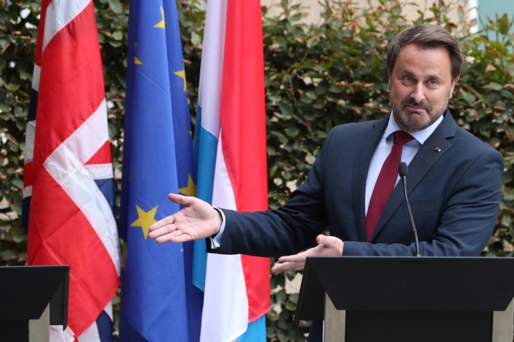 Luxembourg Prime Minister Xavier Bettel gestures to the empty podium where UK Prime Minister was due to stand