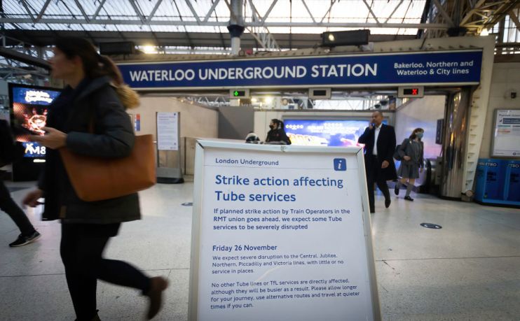 A woman passes a sign informing commuters of imminent strike