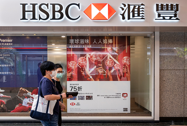Pedestrians walk past the British multinational banking and
