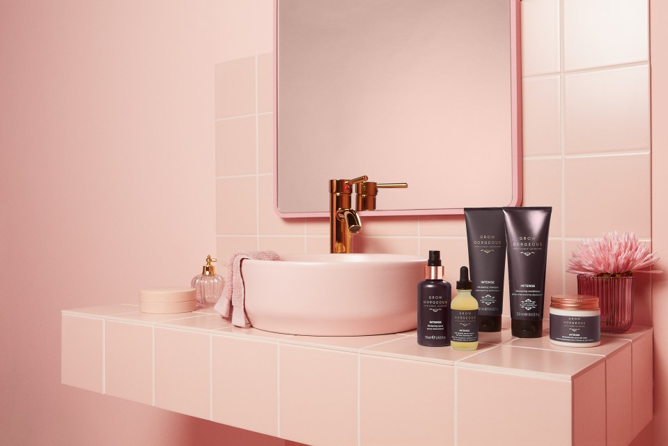 An array of Grow Gorgeous products arranged on a pink bathroom shelf.
