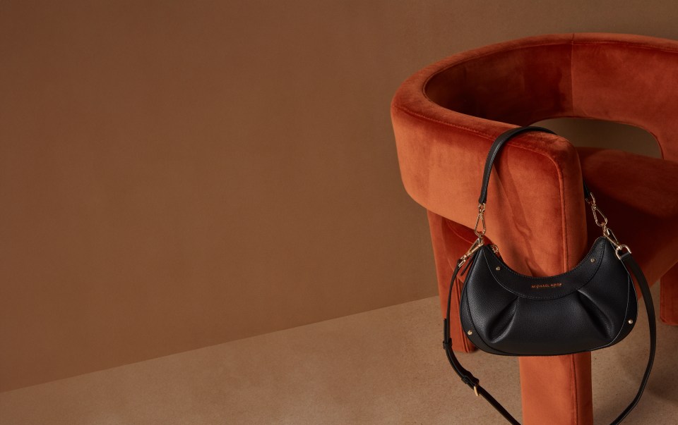 A Micheal Kors bag hanging on a chair.
