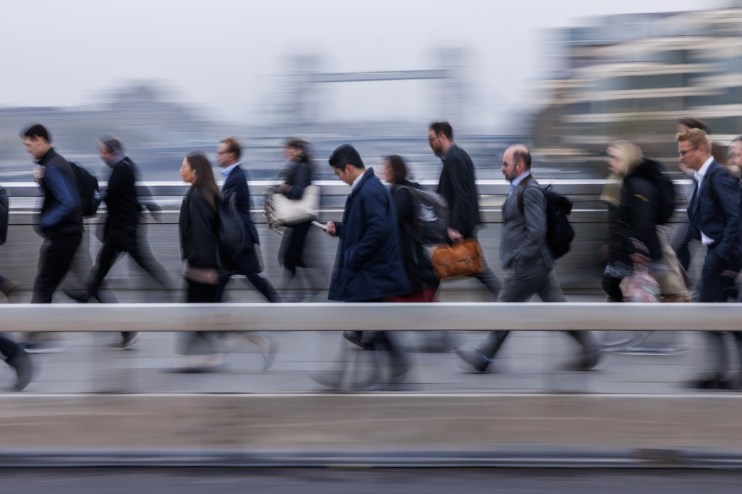Commuters walk across London Bridge