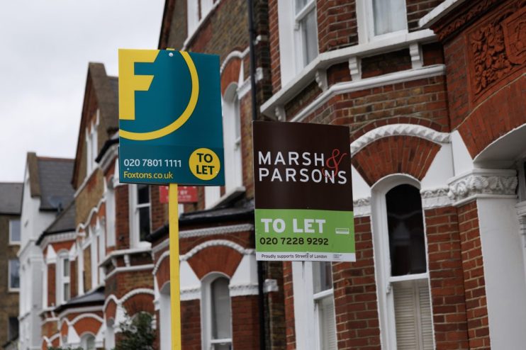 First time buyers celebrating in front of a sold sign, representing a significant increase in mortgage borrowing in 2025.