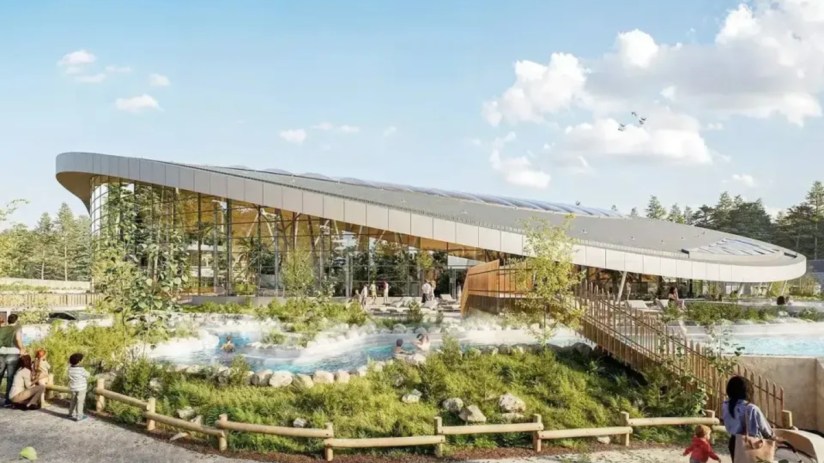 Center Parcs resort aerial view with lush greenery, accommodations, and recreational facilities under clear blue skies