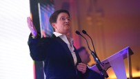 Julia Hoggett speaking at a business conference podium, emphasizing key financial strategies and market insights.