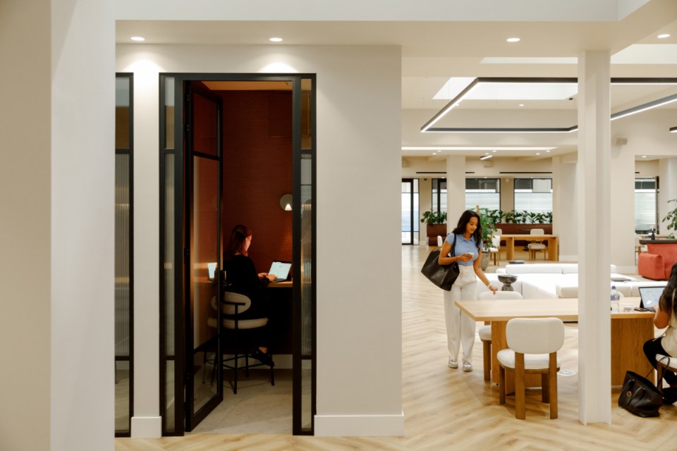 Vintage phone booth transformed into a cozy lounge space with modern seating and ambient lighting in a business setting.