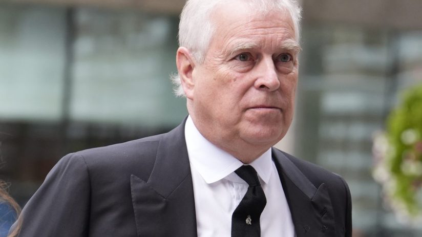 Prince Andrew attending a formal event wearing a suit, engaging in conversation with dignitaries against an elegant backdrop.