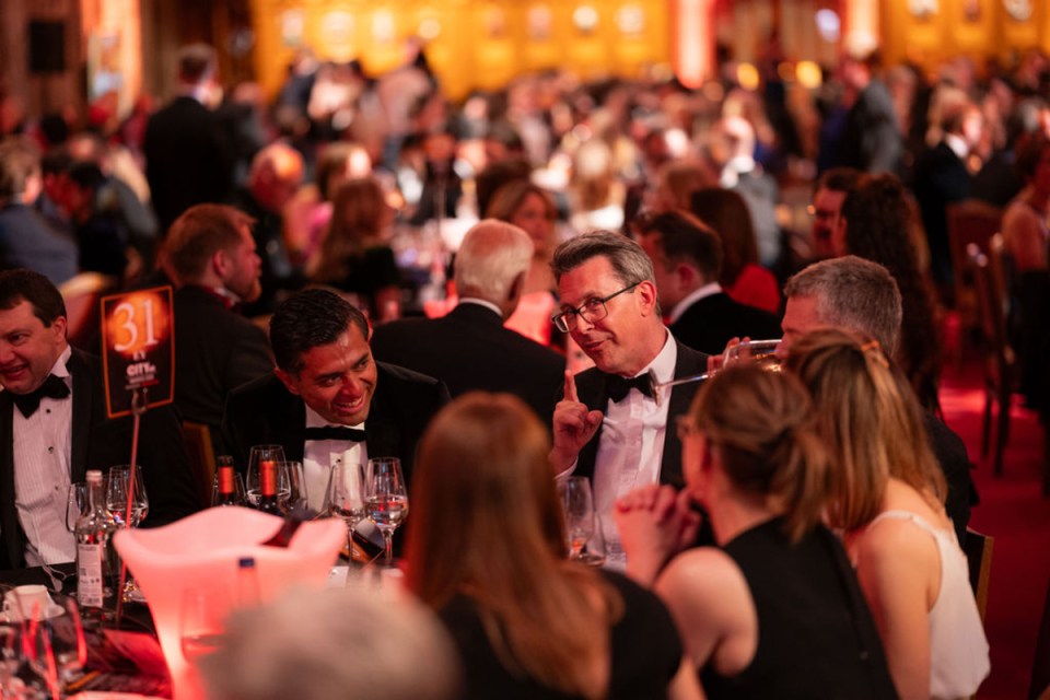 City PM Awards atmosphere with elegant gala setting, attendees in formal attire, glittering lights, and award stage in the...