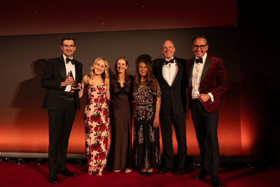 Shawbrook Bank celebrates win at City PM Awards with team on stage holding trophy in formal attire