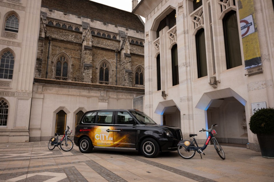 Taxi arriving at City PM Awards venue with illuminated city skyline in the background, highlighting urban business excellence