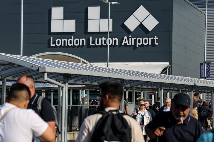 Luton Airport aerial view with planes, runways, and terminal buildings, highlighting busy travel hub operations