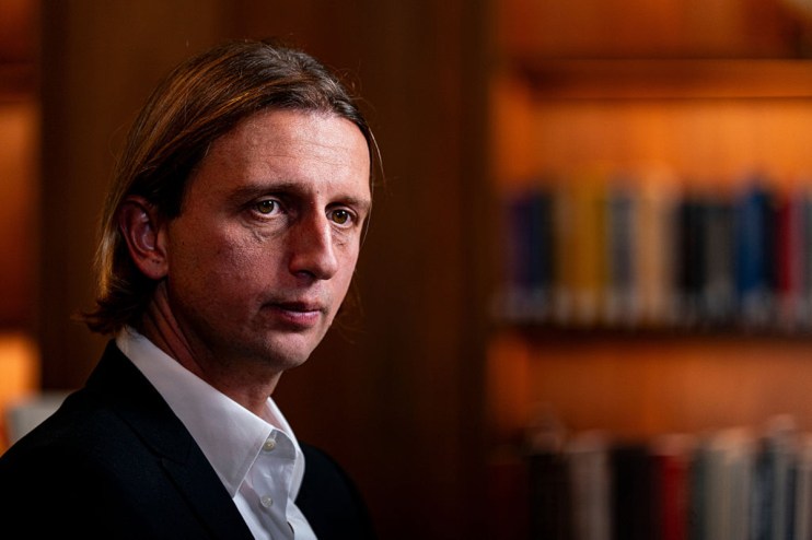 Revolut CEO Nik Storonsky speaking at a business conference, wearing a suit and tie, addressing financial innovation.