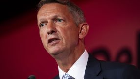 Andy Haldane speaking at a business conference, gesturing with hands, wearing a suit and tie, addressing economic issues.
