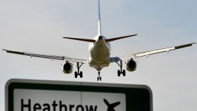 Commercial airplane landing at Heathrow Airport, seen from behind, with a prominent Heathrow sign below.