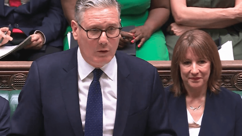 Keir Starmer speaking passionately at Prime Ministers Questions in the UK Parliament chamber, addressing government policies.