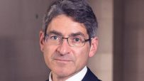 Jonathan Haskel speaking at a business conference, wearing a suit and tie with a focused expression, emphasizing economic ...