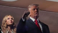 Donald Trump addressing media at a press event, wearing a suit and tie, with reporters and cameras in the background.