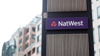 NatWest sign on a dark pillar with vertical slats, set against a blurred background of a modern office building
