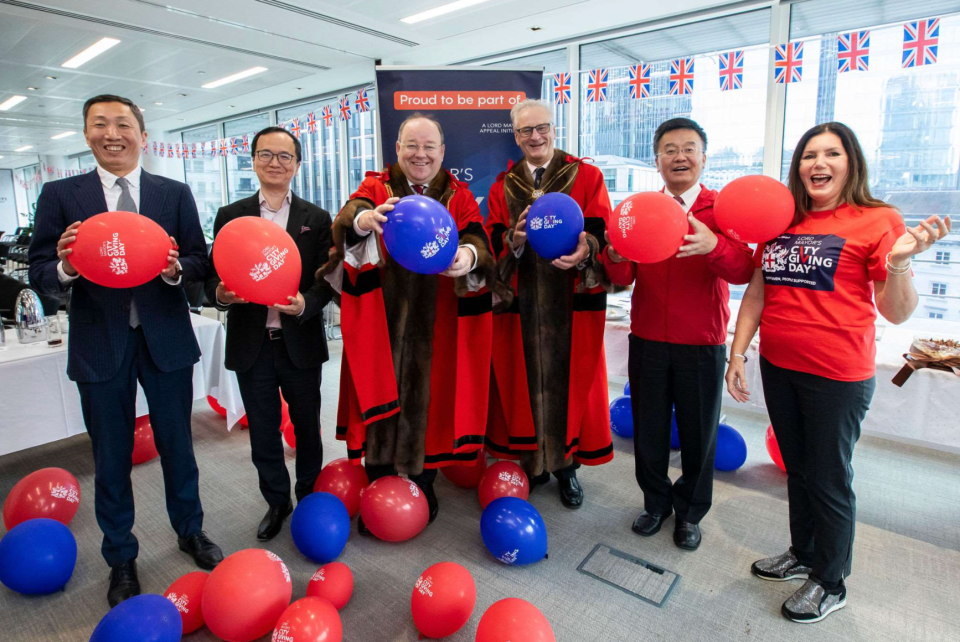 Aldermen and participants holding red and blue City Giving Day balloons at an event