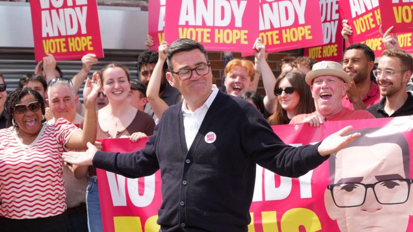 Andy Burnham speaking passionately at a public event, wearing a suit, highlighting his role as a prominent political figure.