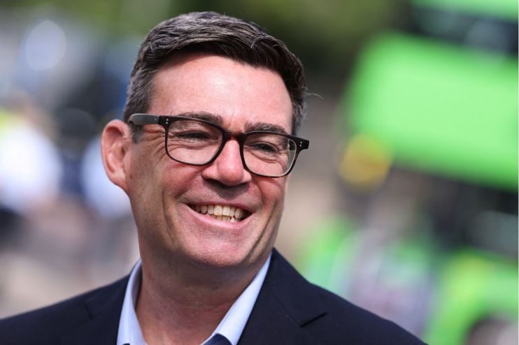 Andy Burnham, Mayor of Greater Manchester, smiling and wearing glasses outdoors.