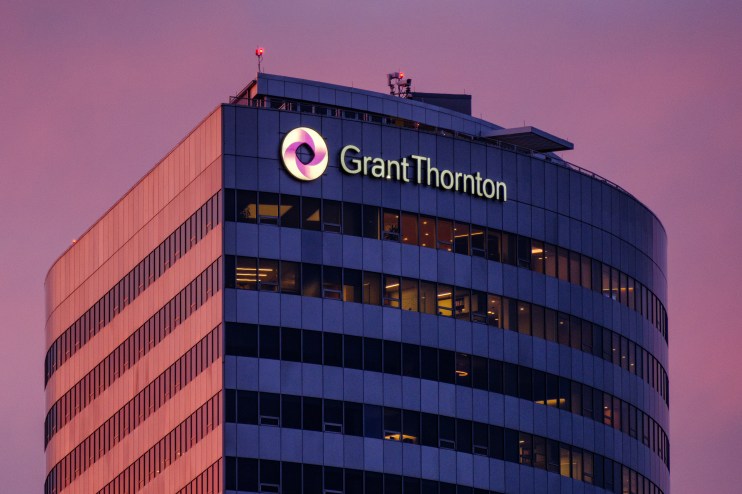 Grant Thornton building exterior with illuminated logo and name against a dramatic pink and purple sky at dusk.