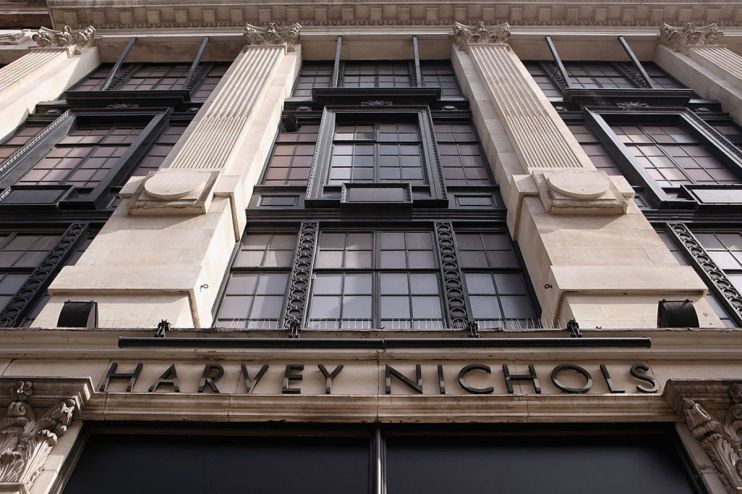 Harvey Nichols storefront featuring elegant window displays and seasonal decorations in a bustling city setting