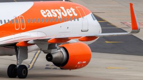 EasyJet aircraft parked at the airport terminal ready for boarding, featuring distinctive orange branding and clear blue sky.
