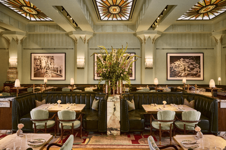 Elegant Dante Mayfair dining room with green booths, marble tables, floral centerpiece, and stained glass ceiling.