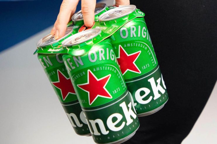 Hand holding a 4-pack of green Heineken beer cans with red stars and white lettering