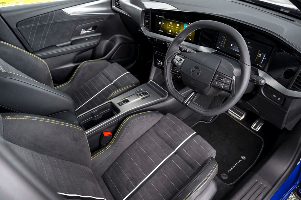Modern car interior featuring black and yellow accented seats, dashboard, steering wheel, and digital display