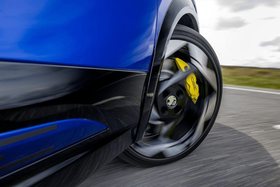 Close-up of a blue cars spinning wheel with bright yellow brake calipers, blurring motion on a road