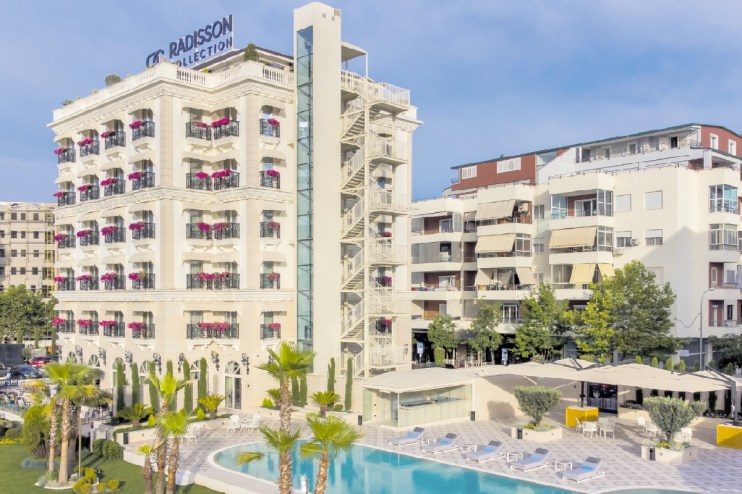 Radisson Collection hotel in Tirana, Albania, featuring a swimming pool, palm trees, and an external fire escape.